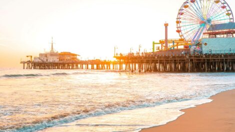 A beachfront view of Santa Monica Pier in Los Angeles, CA, at sunset.