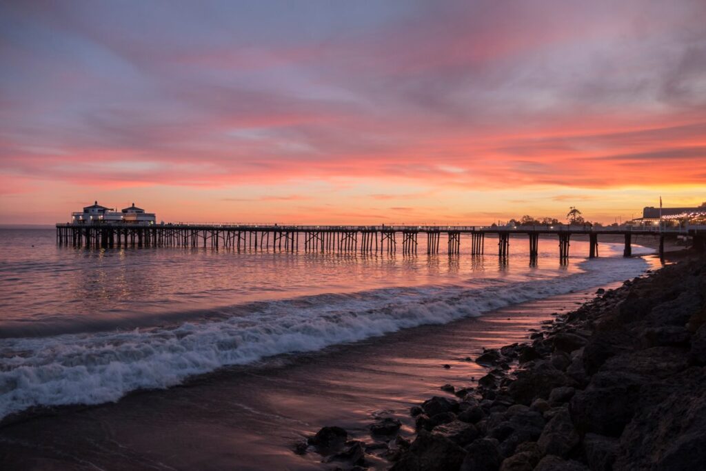 A beachside view of the Malibu Pier at sunset.