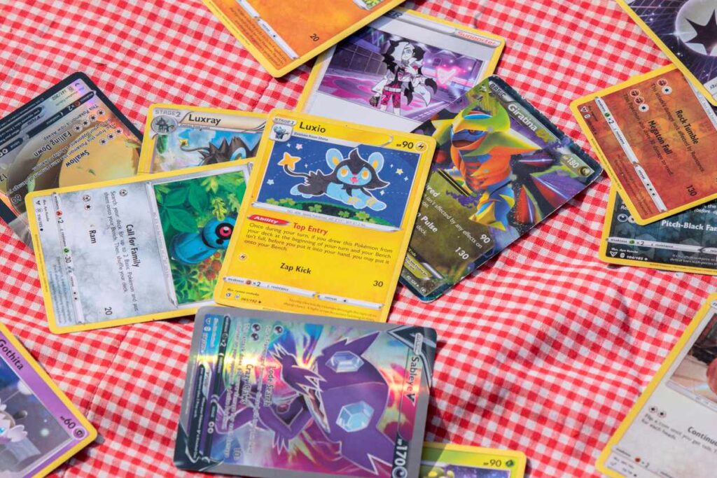 Colorful Pokemon cards scattered across a red and white checkered tablecloth.