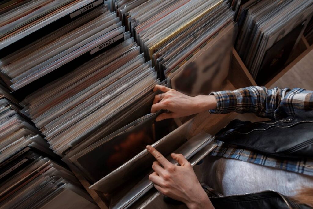 A person flips through vinyl records covered with protective cover sleeves.