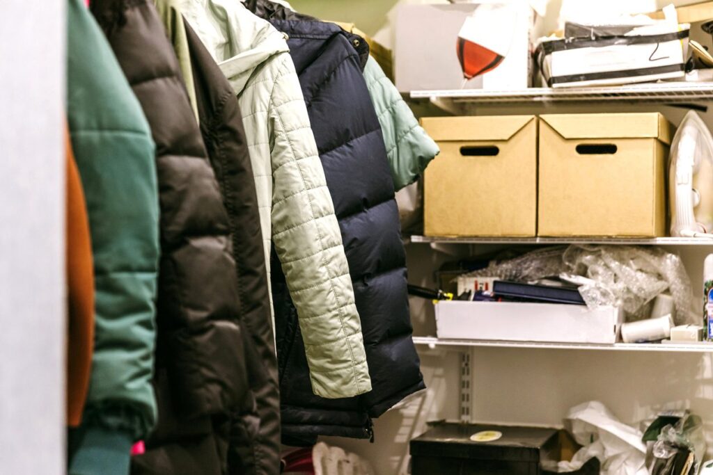 A home closet filled with coats, boxes, and household supplies.