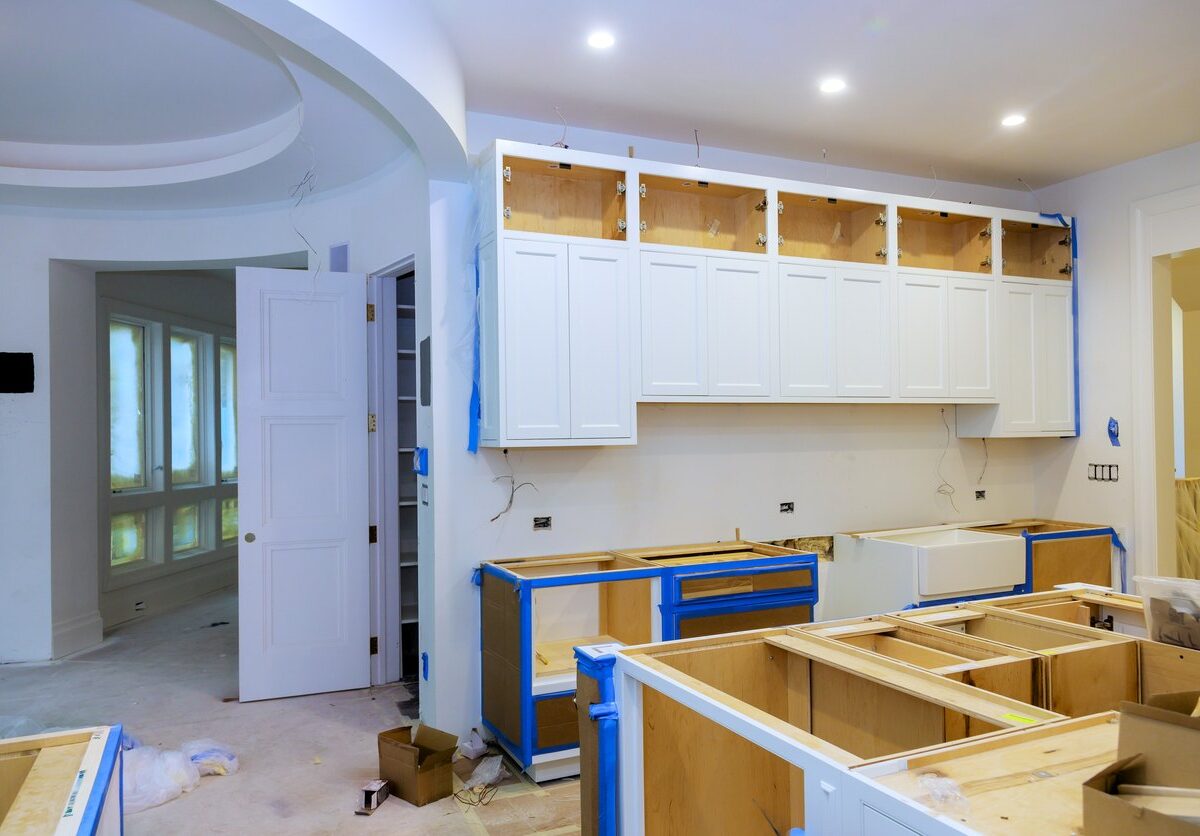 A home kitchen mid-renovation with new cabinets, wiring, and white paint.