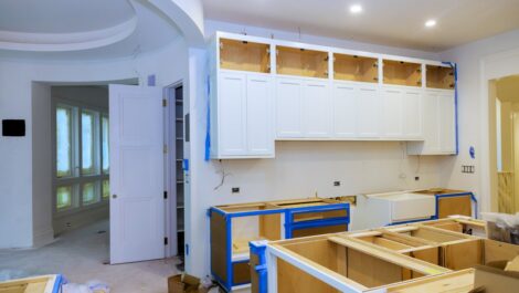 A home kitchen mid-renovation with new cabinets, wiring, and white paint.